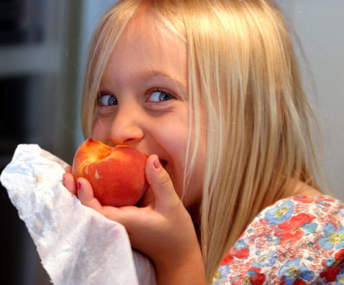 A child eating a peach fruit